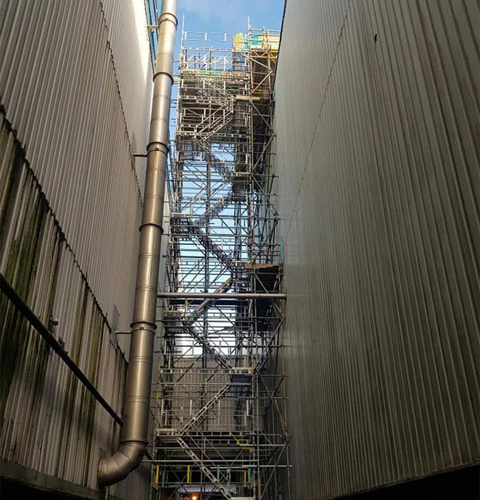 Scaffolding tower scaling side of warehouse