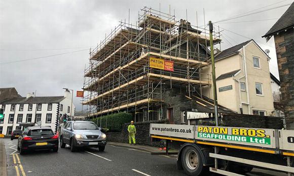 Scaffolding covering house in Cumbria with Paton Bros Flatbed on road